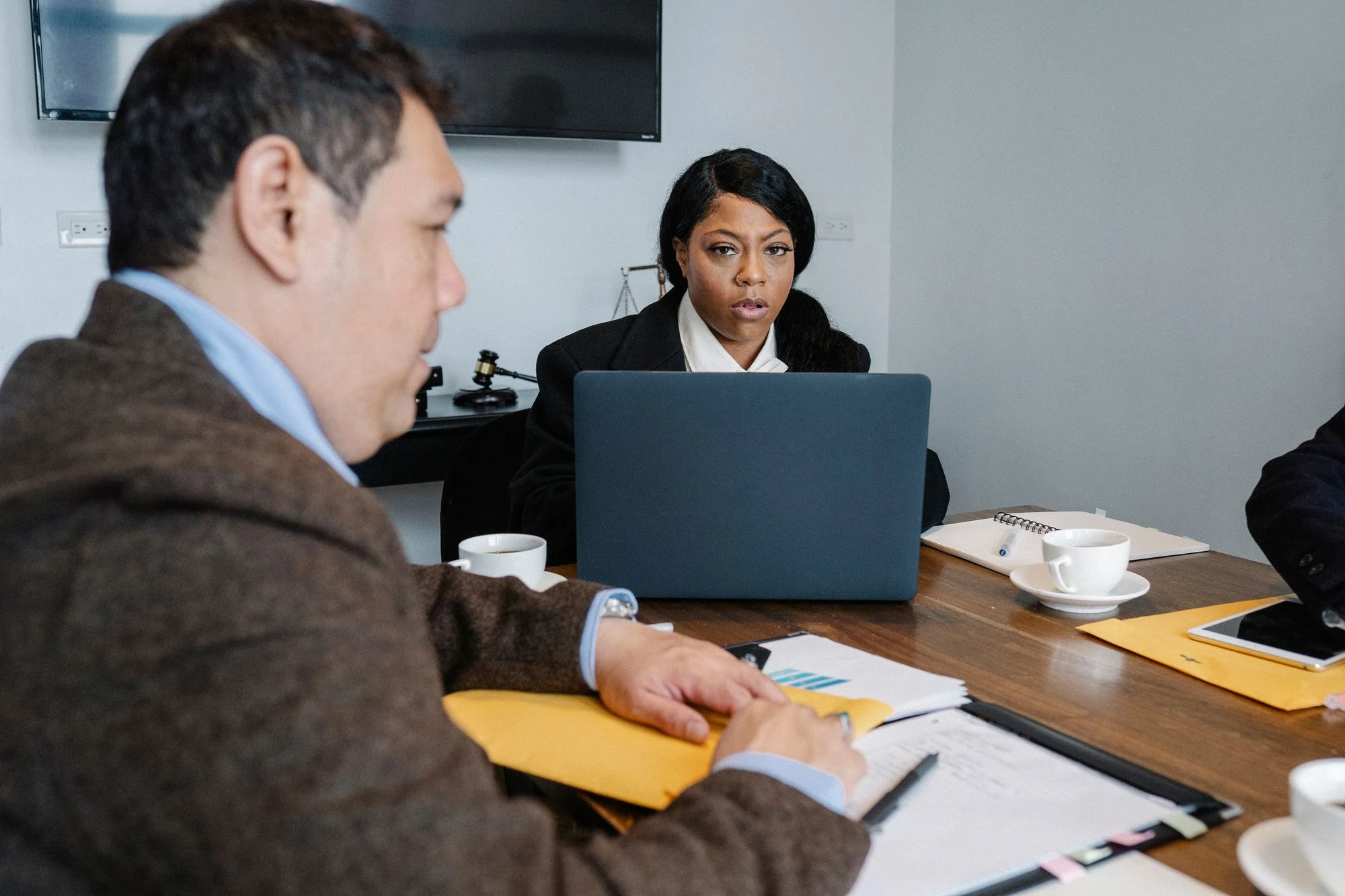 Group of multiethnic coworkers in formal wear sitting at table with laptop and documents while discussing business issues