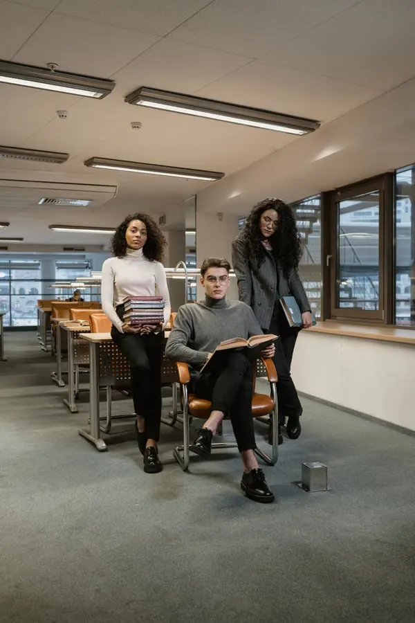 Three young college students studying together in a modern library setting.