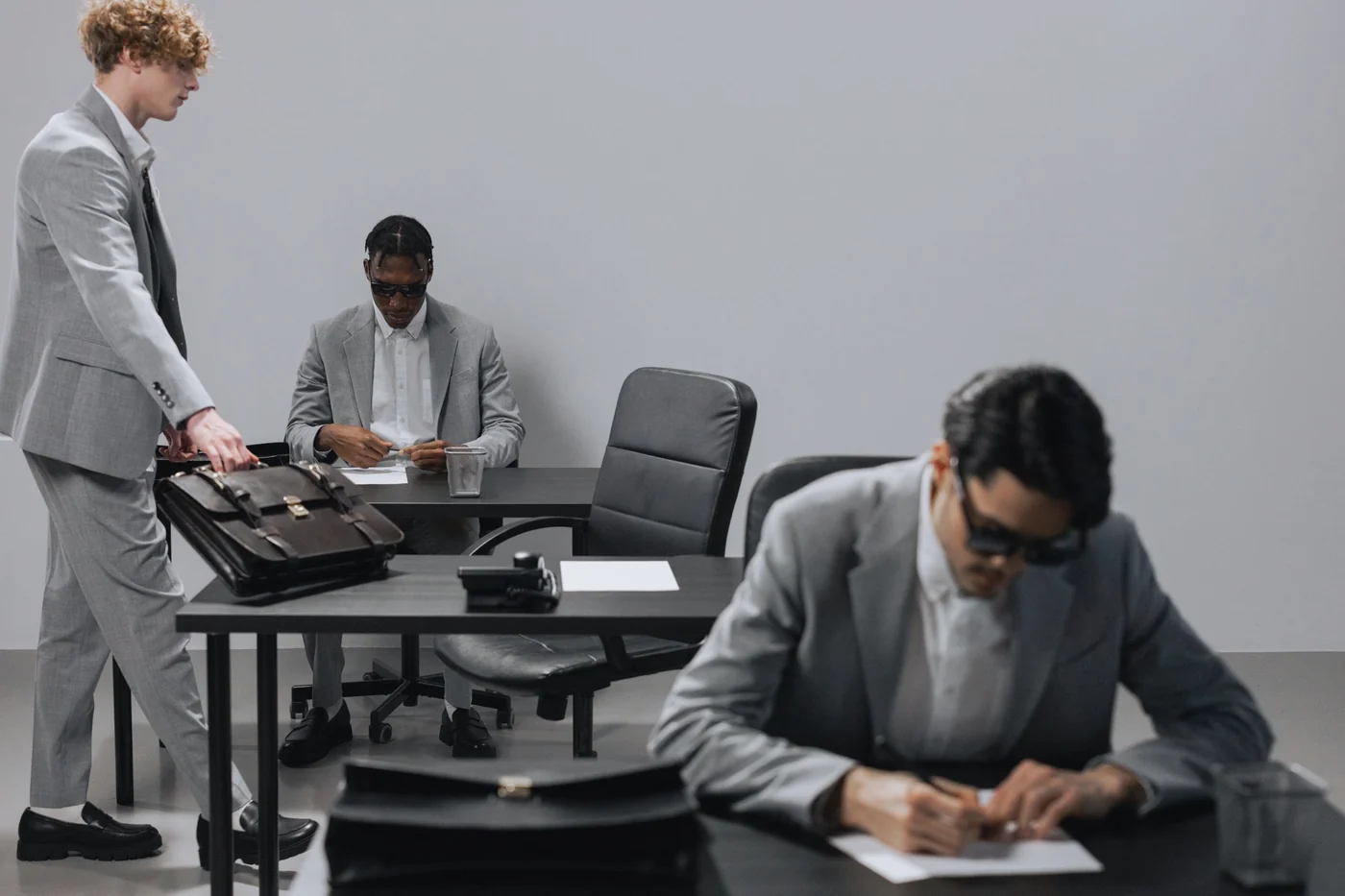 Business office with diverse employees in gray suits working at desks in an indoor setting.